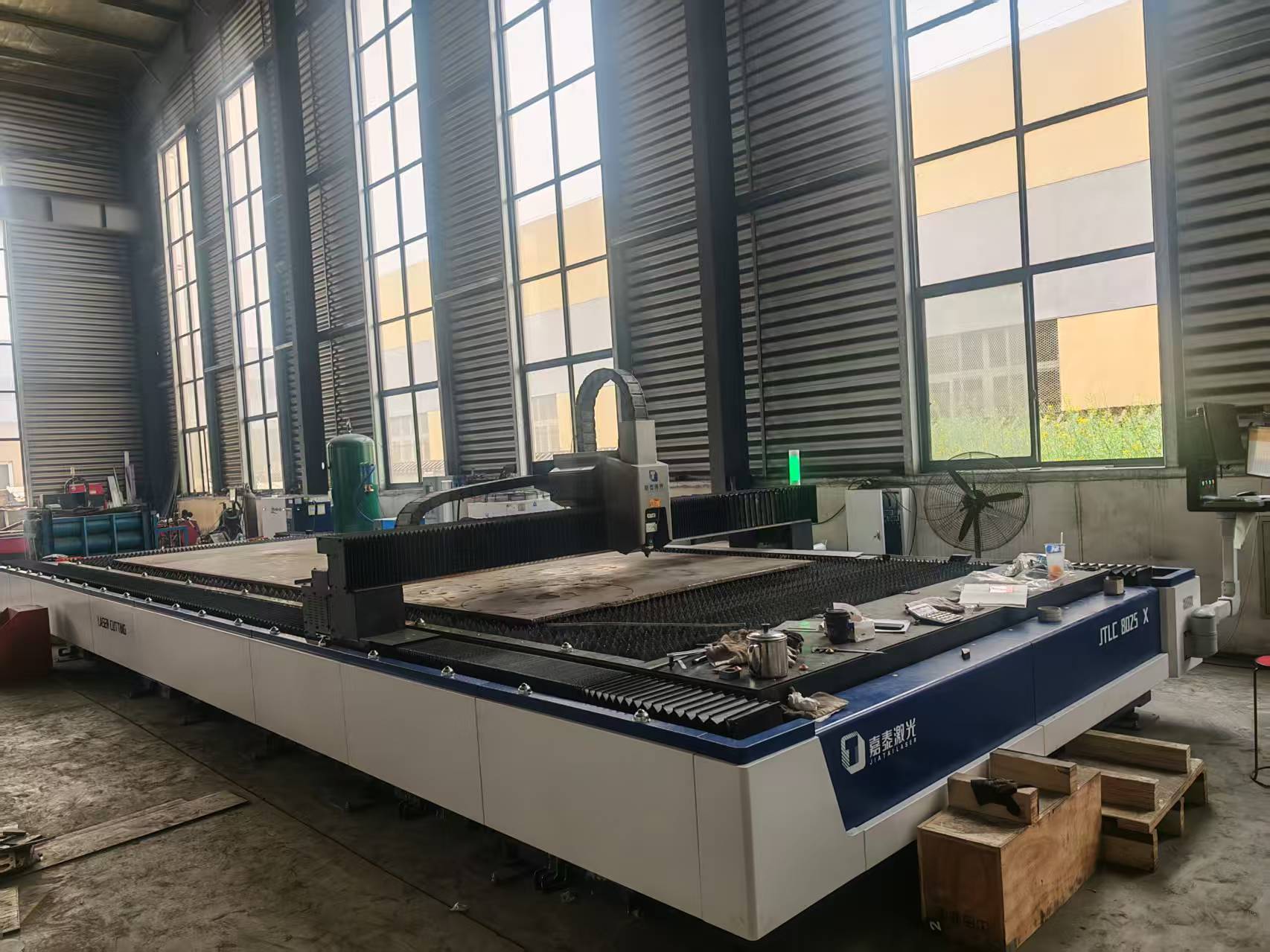 Fiber laser cutting machine positioned over a steel plate on the workshop floor